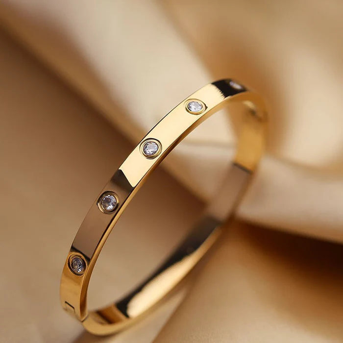 Gold bracelet with embedded diamonds on a beige background